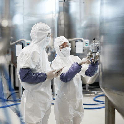 Image of two production workers at a pharmaceutical manufacturing plant.